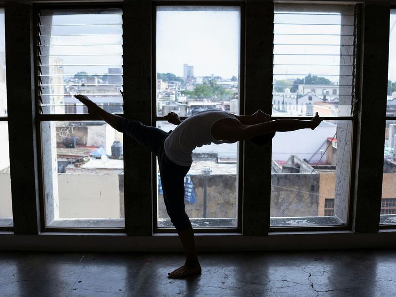 Silhouette of a person in a dynamic yoga flow pose with cobalt blue light trails.